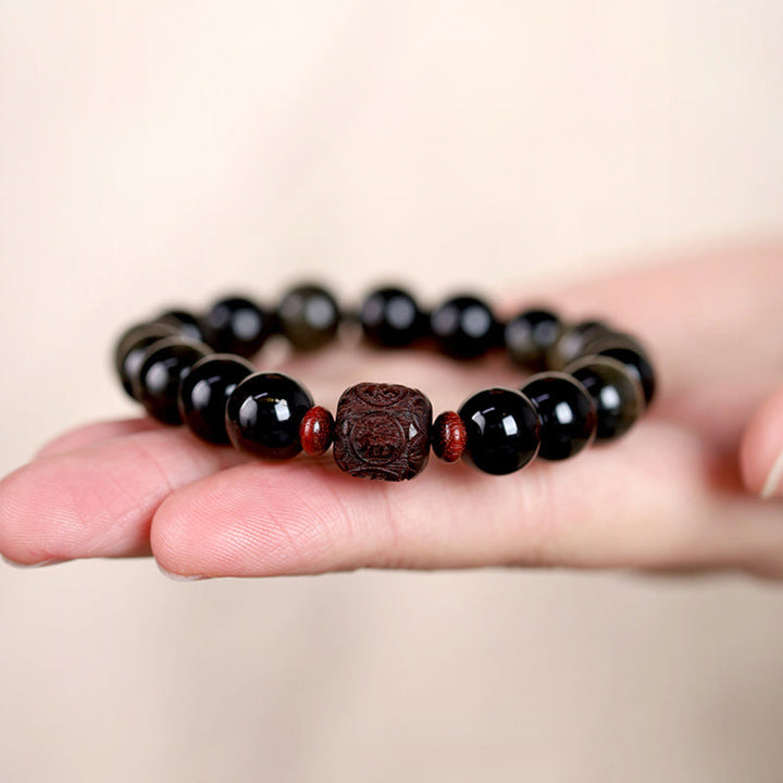 Schwarzes Obsidian Armband mit Om Symbol Anhänger am Handgelenk.