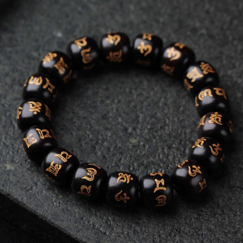 Schwarzes Ebenholz Armband mit goldenen Om Mani Padme Hum Symbolen elegant arrangiert.