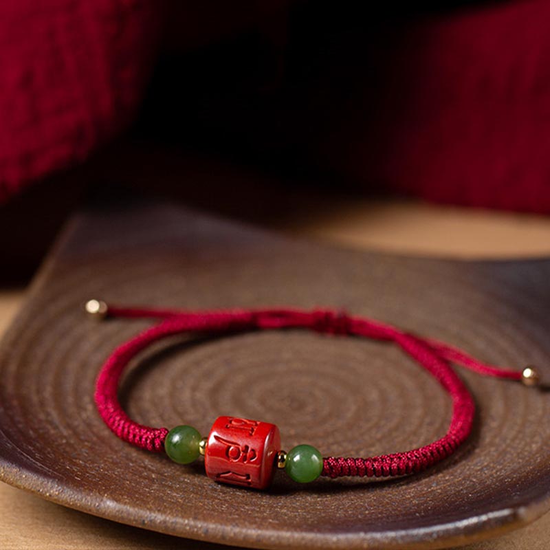 Rotes Armband mit grünen Jadekugeln auf Holzuntergrund elegant.