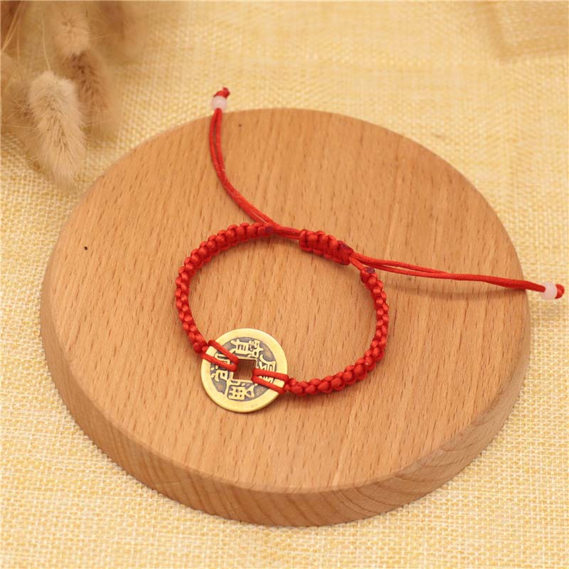 Rotes Armband Kupfer – Glück mit goldenem Münzanhänger Holzoberfläche