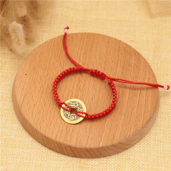 Rotes Armband Kupfer – Glück mit goldenem Münzanhänger Holzoberfläche