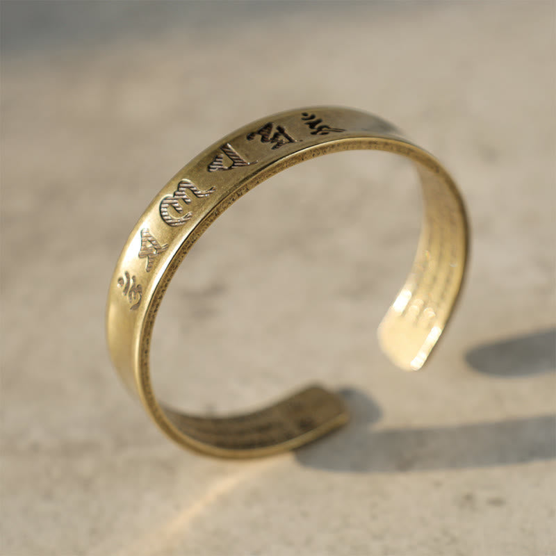 Goldenes Armband Tibet Buddha Mantra auf hellem Untergrund Nahaufnahme