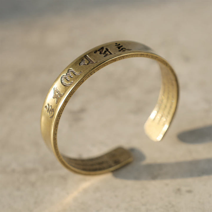 Goldenes Armband Tibet Buddha Mantra auf hellem Untergrund Nahaufnahme