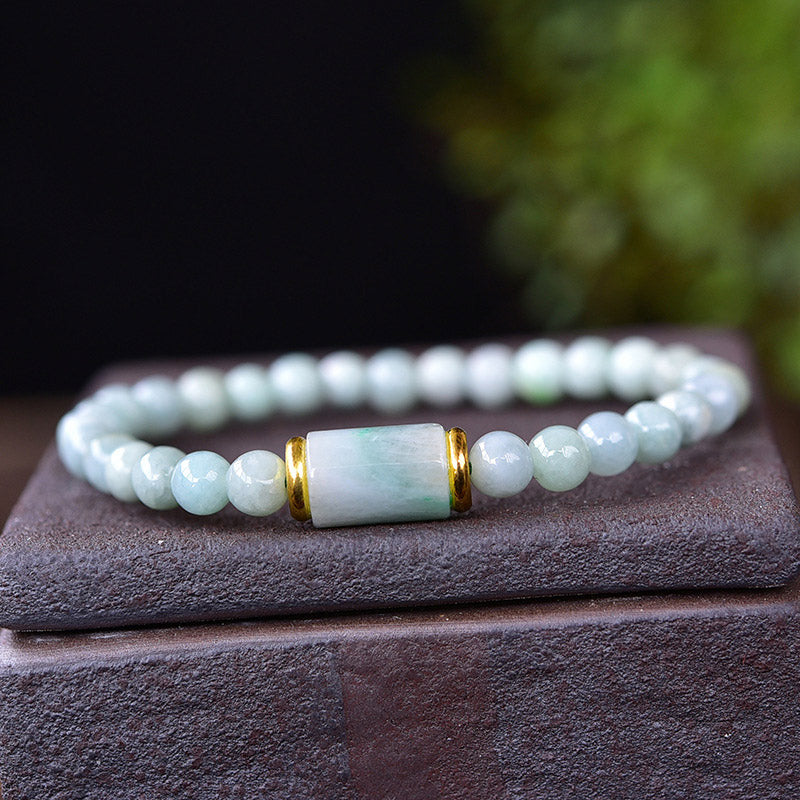 Jade Armband mit weißen Perlen und goldenem Zylinder elegant präsentiert.