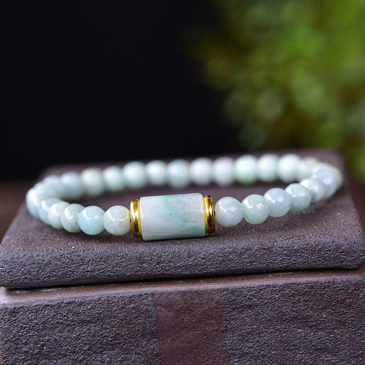 Jade Armband mit weißen Perlen und goldenem Zylinder elegant präsentiert.