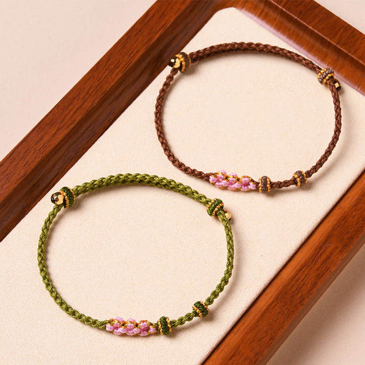 Zwei Armbänder mit Pfirsichblüte-Design in Grün und Braun.
