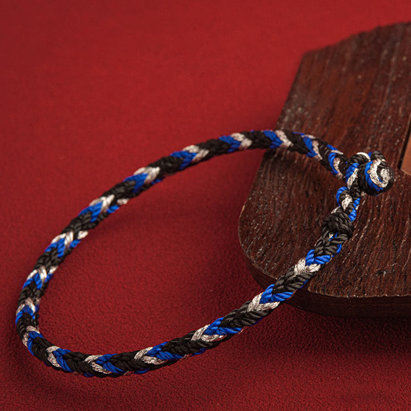 Mehrfarbiges Glücksband Armband in Blau Schwarz Weiß auf Holz