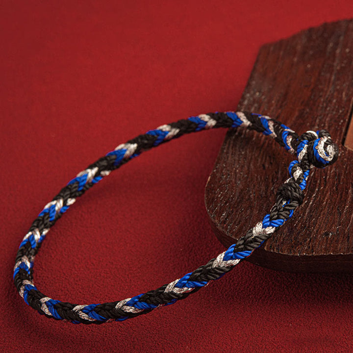 Mehrfarbiges Glücksband Armband in Blau Schwarz Weiß auf Holz