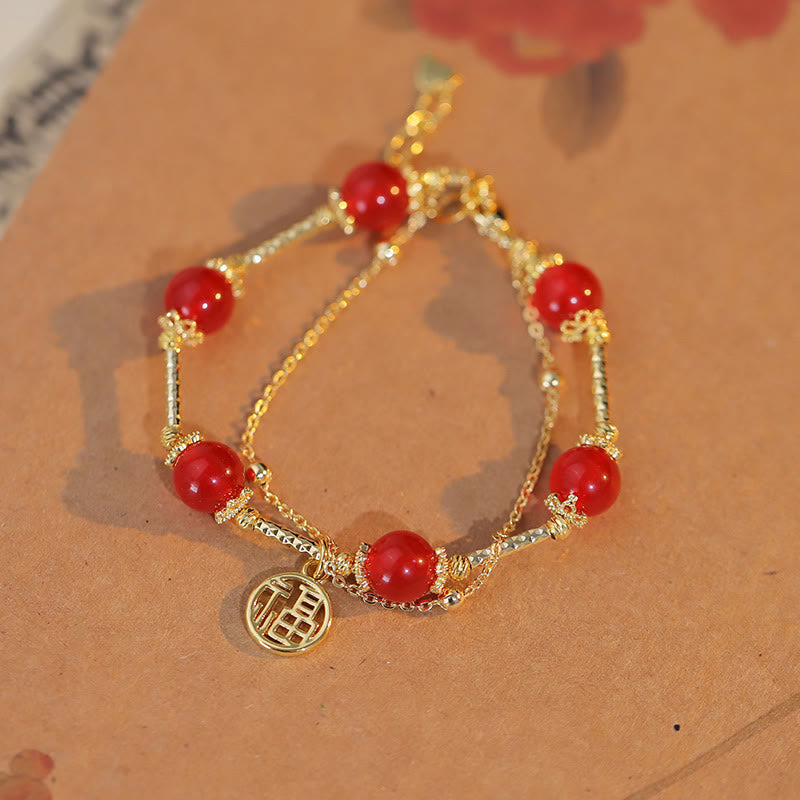 Armband Roter Achat Fu-Zeichen mit goldenem Charm am Handgelenk.