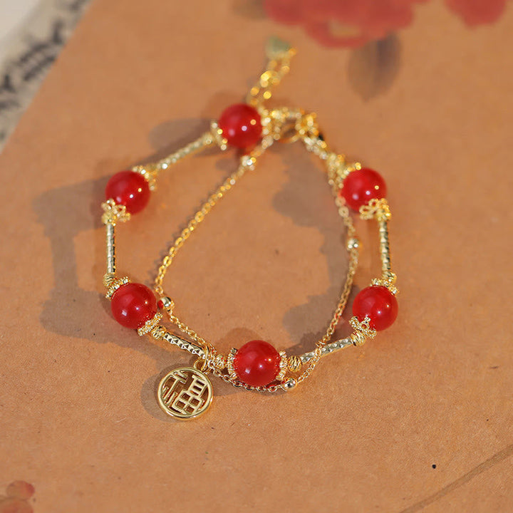Armband Roter Achat Fu-Zeichen mit goldenem Charm am Handgelenk.