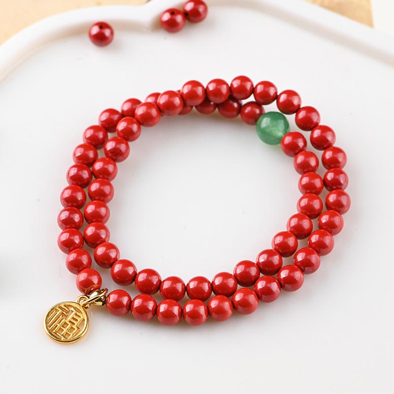 Rotes Perlenarmband mit grünem Aventurin und goldenem Anhänger.