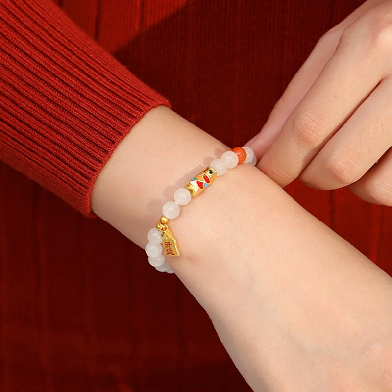 Weißes Jade Armband mit Koi Fisch Charm am Handgelenk getragen