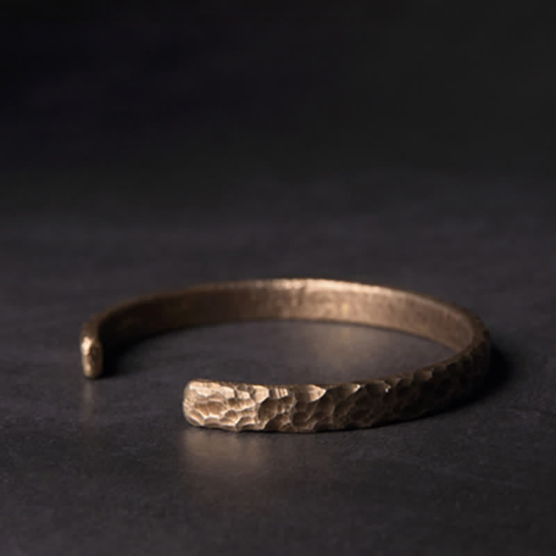 Kupfer Armband mit gehämmerter Oberfläche auf dunklem Hintergrund liegt.