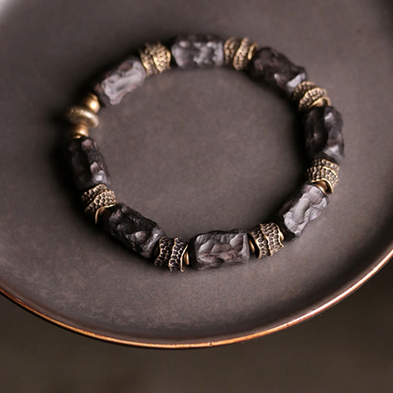 Armband Kupfer Ebenholz mit Perlen auf grauem Hintergrund elegant.