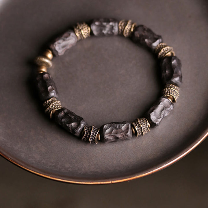 Armband Kupfer Ebenholz mit Perlen auf grauem Hintergrund elegant.