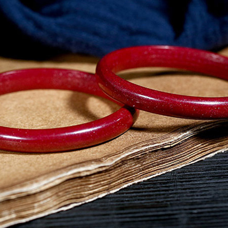 Rotes Armband Zinnober Herzsutra Segen auf Holzbuch elegantes Design.