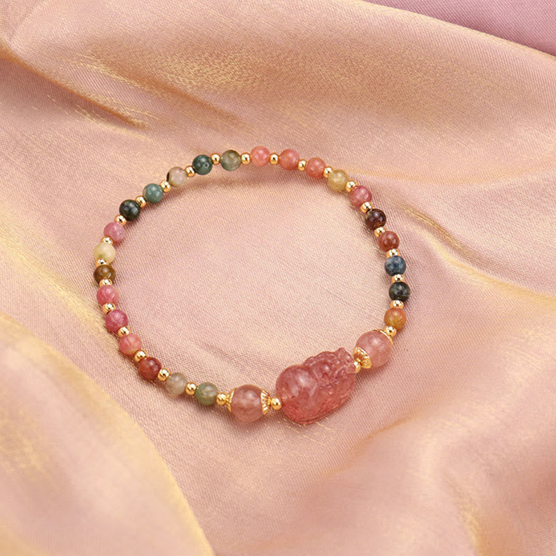 Armband mit Erdbeerquarz und Mondstein auf rosa Stoff.
