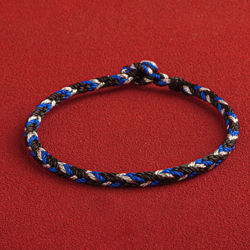Glücksband Armband mehrfarbig blau schwarz weiß Flachaufnahme rotes Hintergrund
