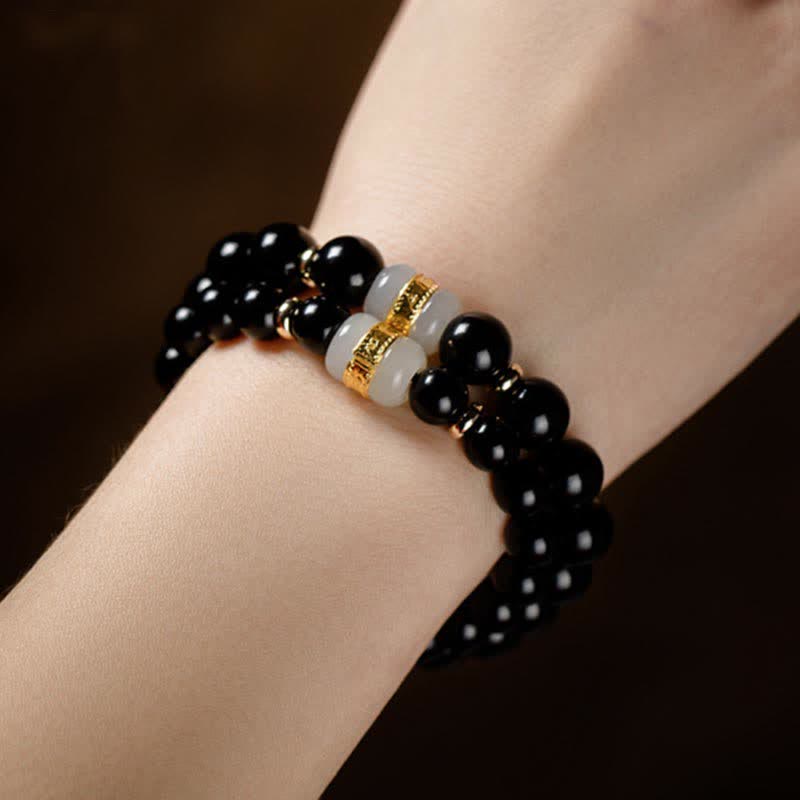 Schwarzes Obsidian Armband mit goldenen Om Mani Padme Hum Perlen am Handgelenk