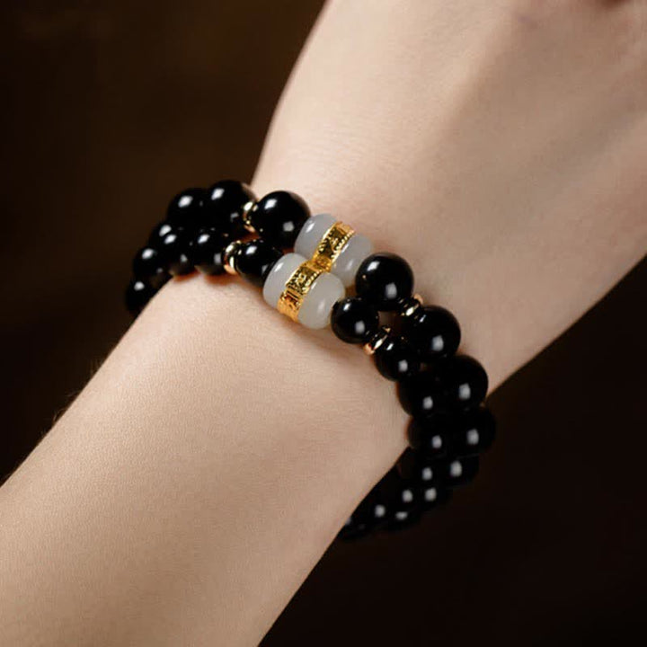 Schwarzes Obsidian Armband mit goldenen Om Mani Padme Hum Perlen am Handgelenk