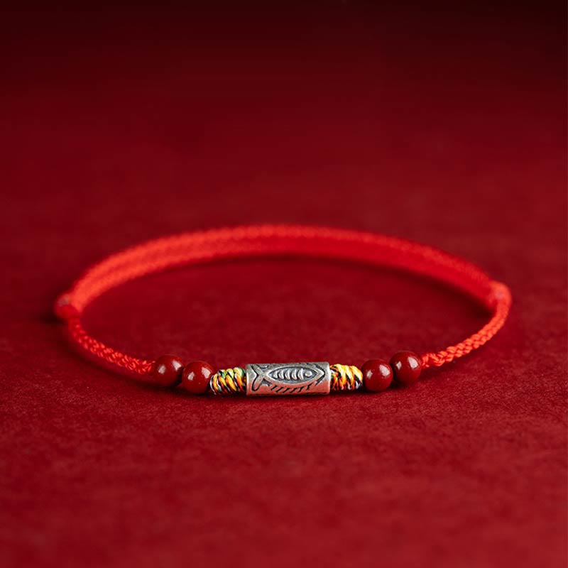Rotes Armband mit Perlen und verziertem Mittelteil auf rotem Hintergrund.