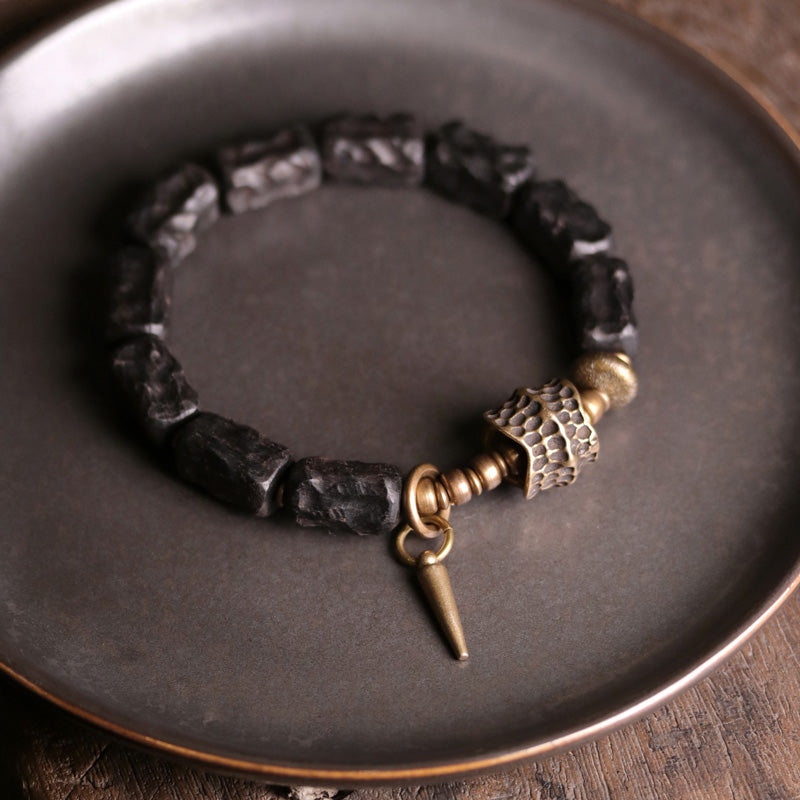 Schwarzes Ebenholz Armband mit Kupfer Details auf grauem Teller