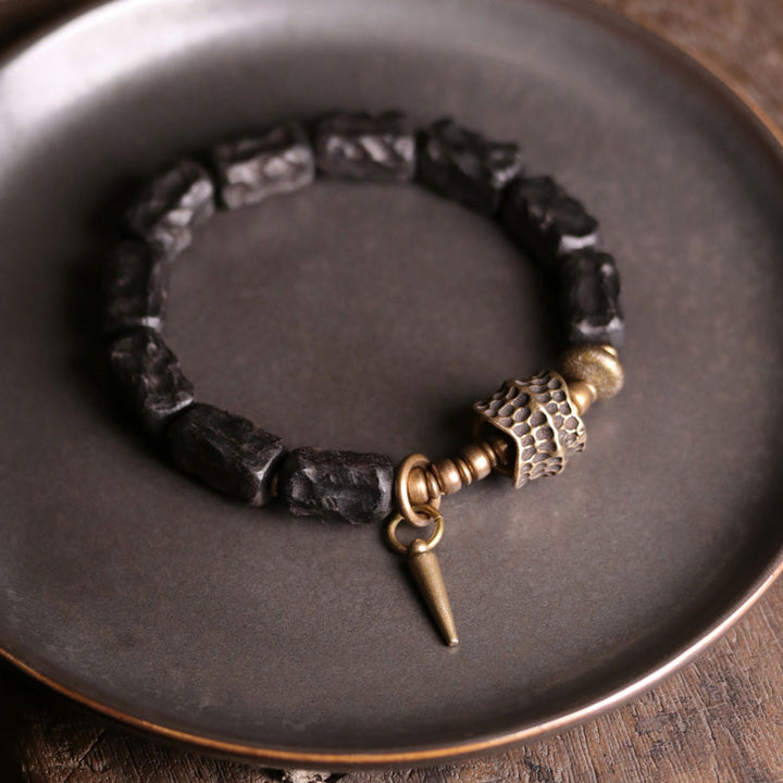 Schwarzes Ebenholz Armband mit Kupfer Details auf grauem Teller