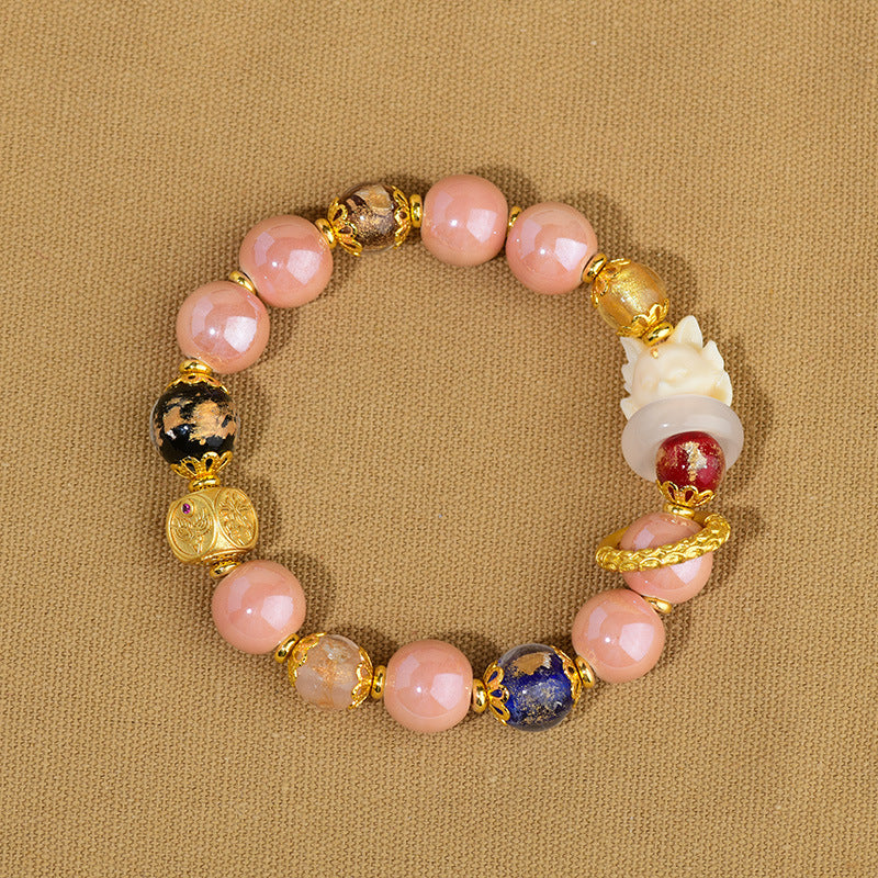 Rosenquarz Armband mit goldenen Perlen und Glückssymbolen elegant.