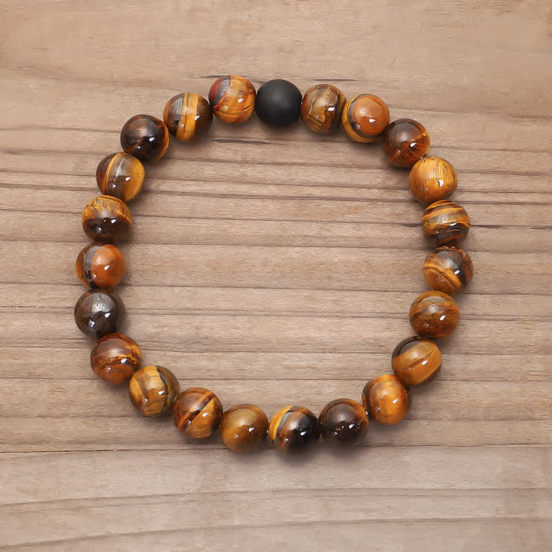 Mala 108 Perlen Tigerauge Armband mit schwarzer Kugel auf Holz.