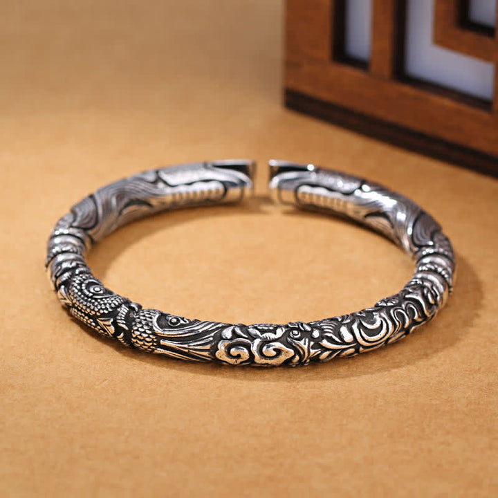 Silbernes Drachen-Armband mit aufwendigen Gravuren auf beigem Hintergrund.