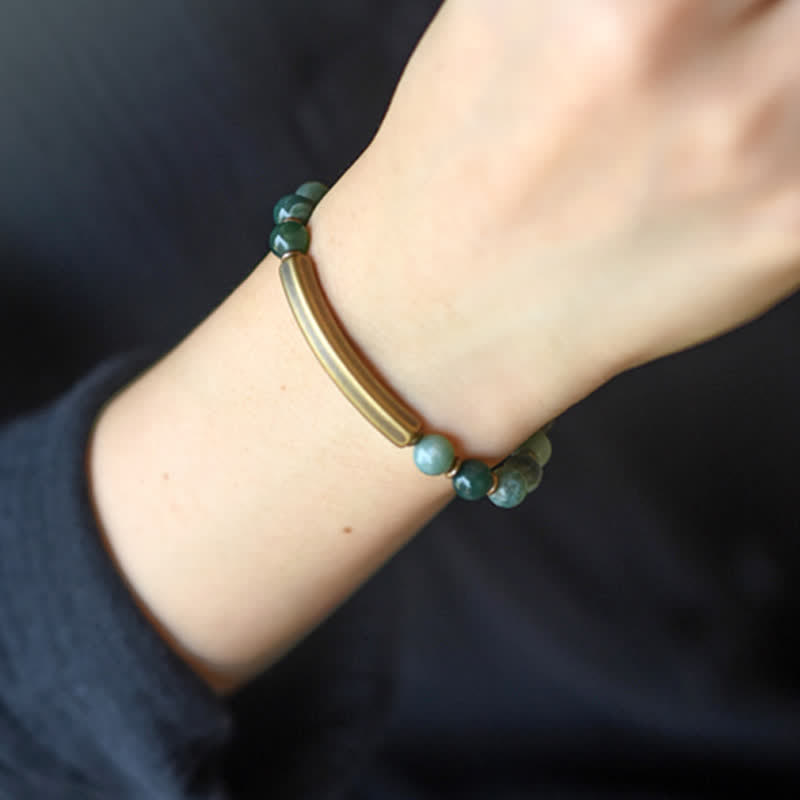 Armband mit grünen Steinen und Metallstab am Handgelenk getragen elegant