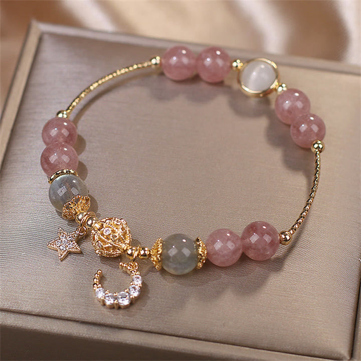 Elegantes Armband mit rosafarbenem Erdbeerquarz und Mondstein auf Präsentationstablett.