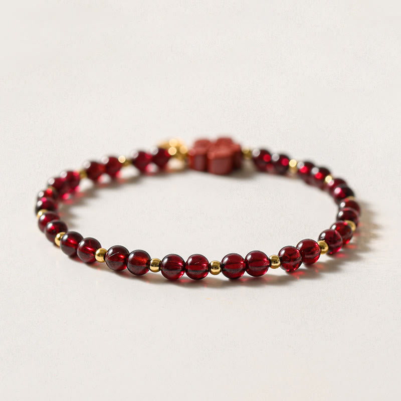 Rotes Granat Armband mit Goldperlen auf neutralem Hintergrund, Draufsicht