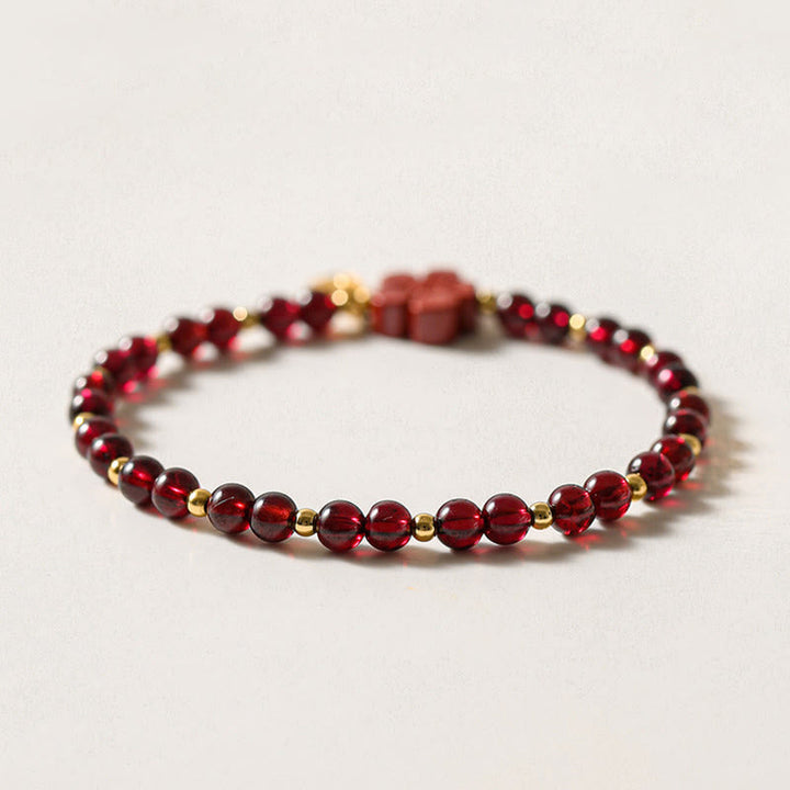Rotes Granat Armband mit Goldperlen auf neutralem Hintergrund, Draufsicht