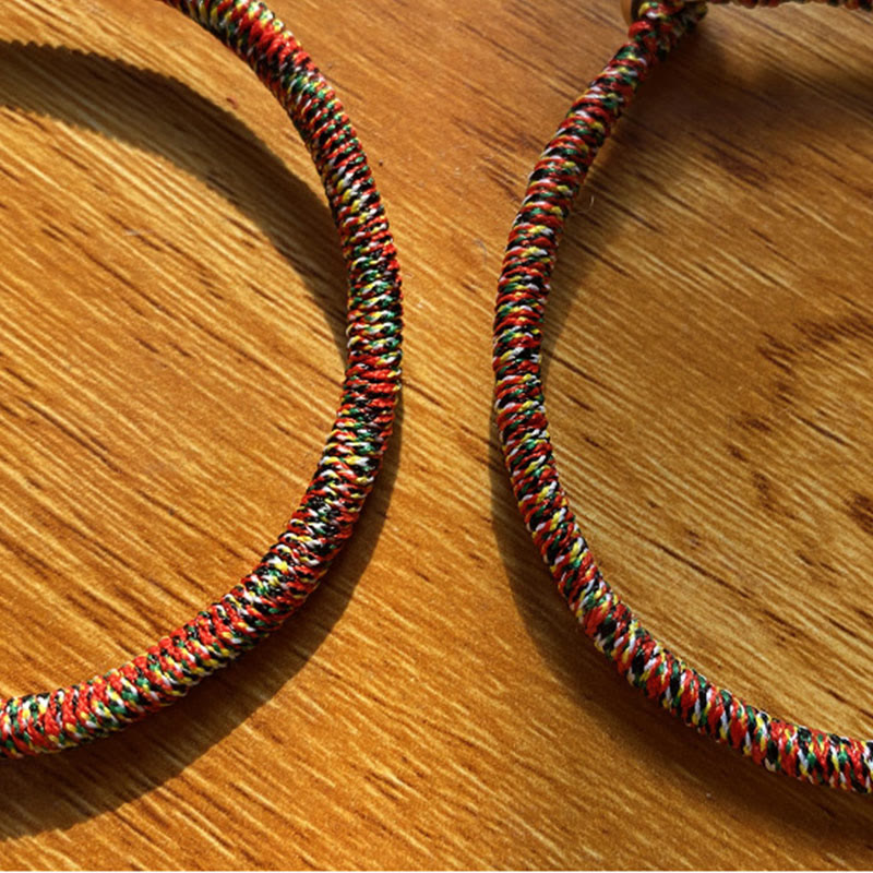 Bunte geflochtene Armbänder auf Holzoberfläche nebeneinander liegend.