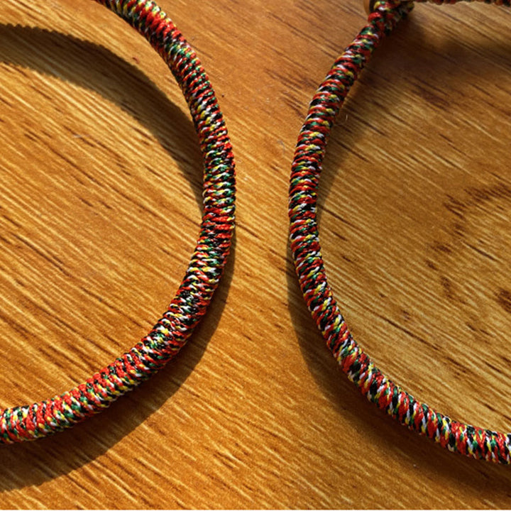 Bunte geflochtene Armbänder auf Holzoberfläche nebeneinander liegend.