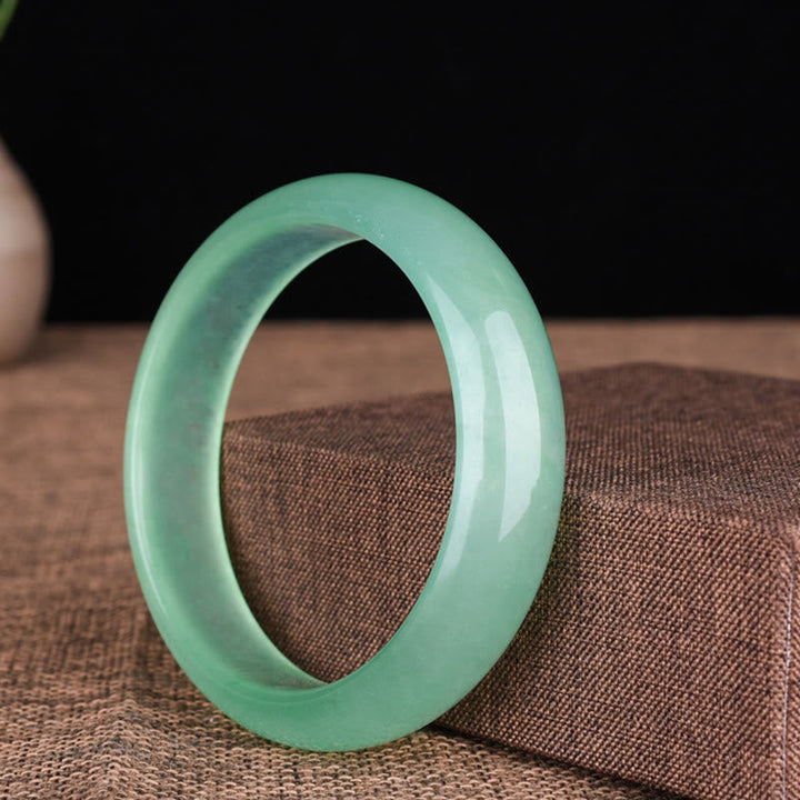 Grünes Jade Armband glänzend poliert auf Stoffuntergrund elegant.