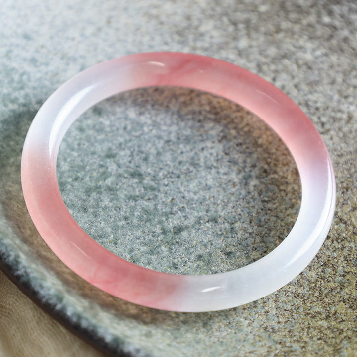Rosa weißes Jade Armband Armreif auf Sanduntergrund Flachaufnahme