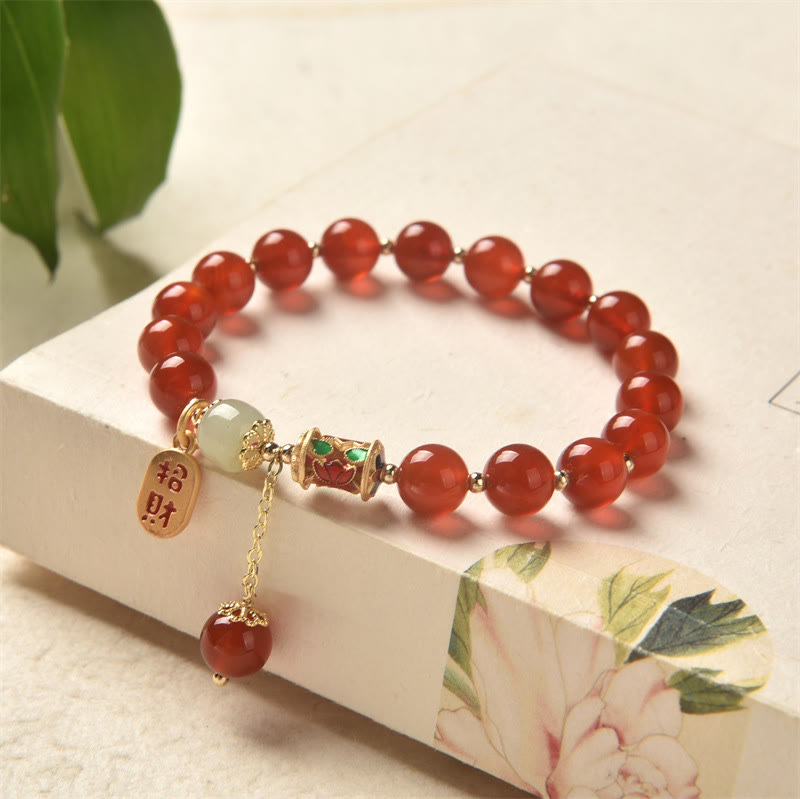 Armband Roter Achat Jade mit goldenen Charms elegant präsentiert.