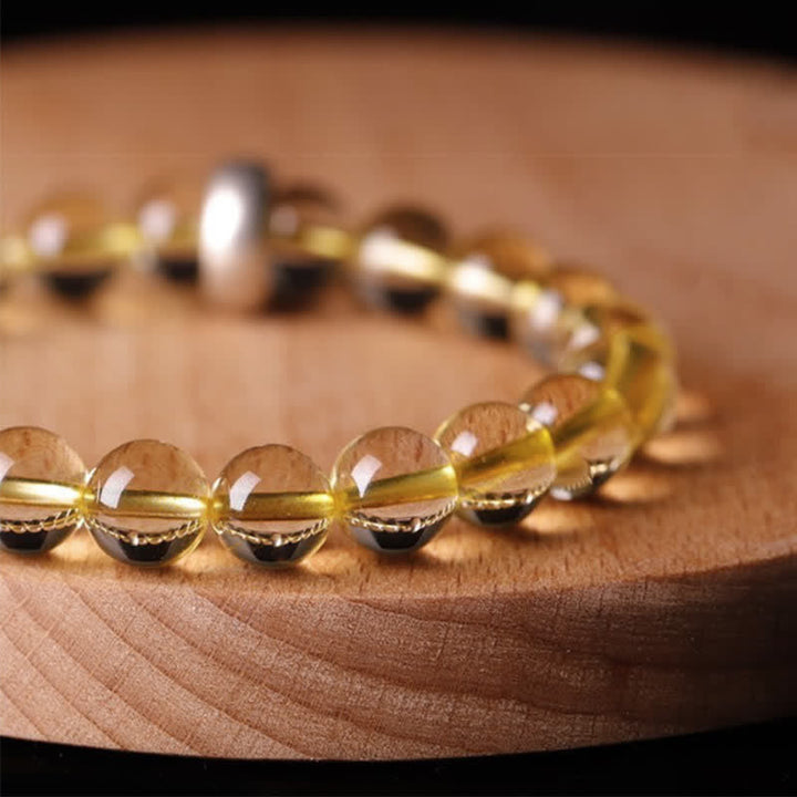 Citrin Armband mit goldenen Perlen auf Holzoberfläche elegant.