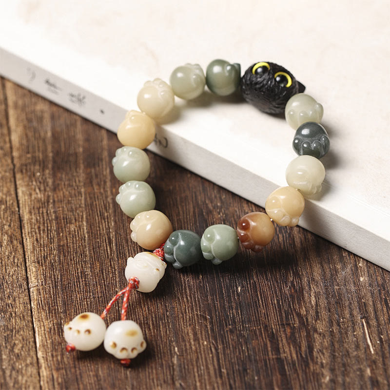 Armband Bodhi Ebenholz Katze mit Perlen auf Holzoberfläche.