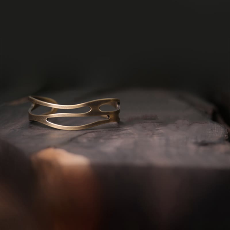 Kupfer Armband mit wellenförmigem Design auf Stein Oberfläche.