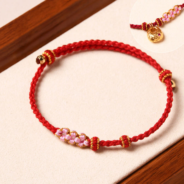 Rotes Armband Pfirsichblüte – Schutz mit rosa Perlen und Goldakzenten.