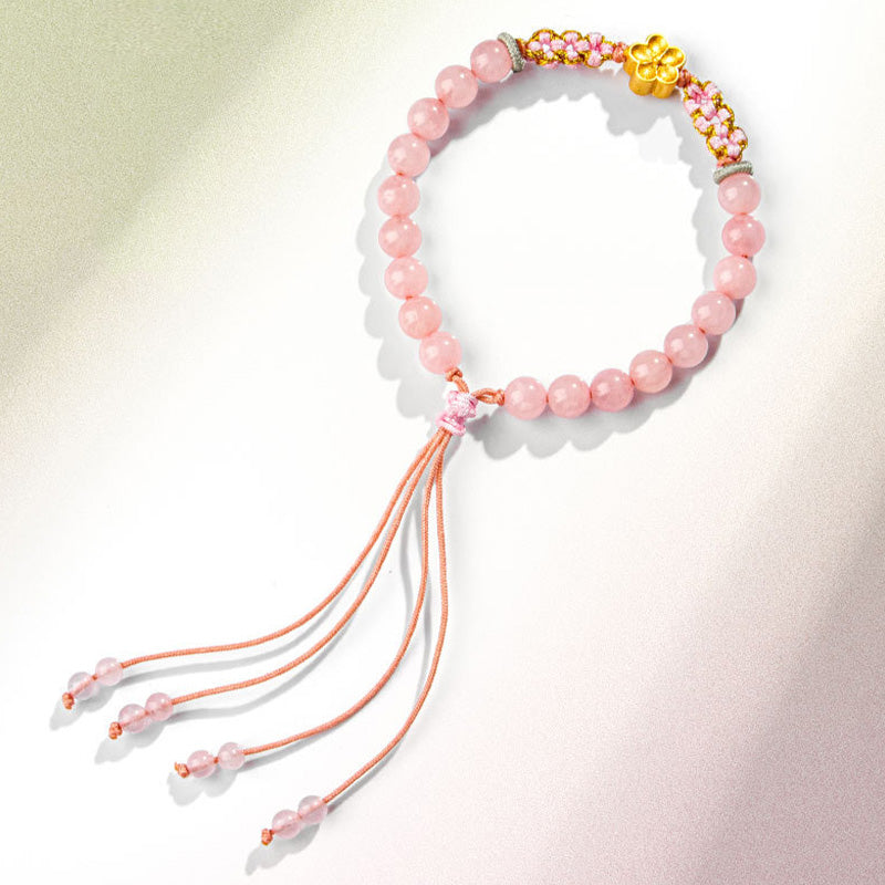 Rosenquarz Armband mit rosa Perlen und orange Quasten elastisch.