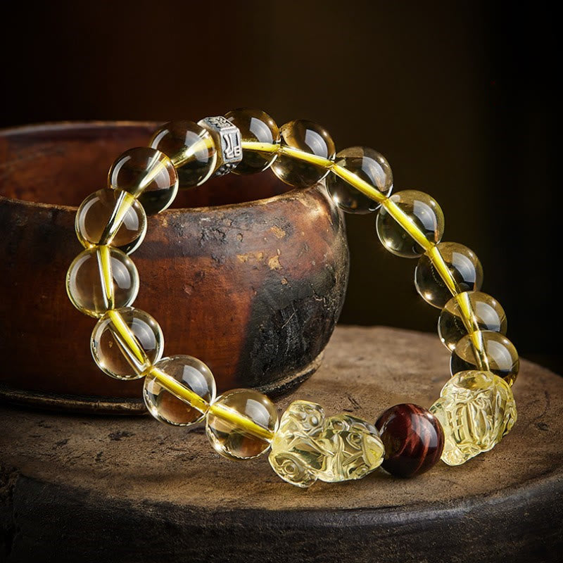 Armband mit Tigerauge, Citrin und Pixiu Perlen auf Holzoberfläche.