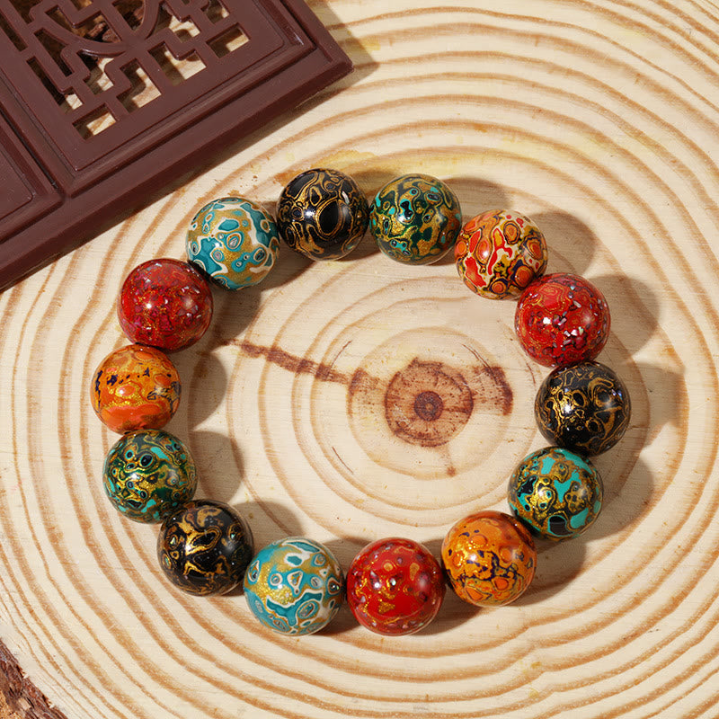 Buntes Lackperlen Armband mit geometrischen Mustern auf Holzoberfläche.