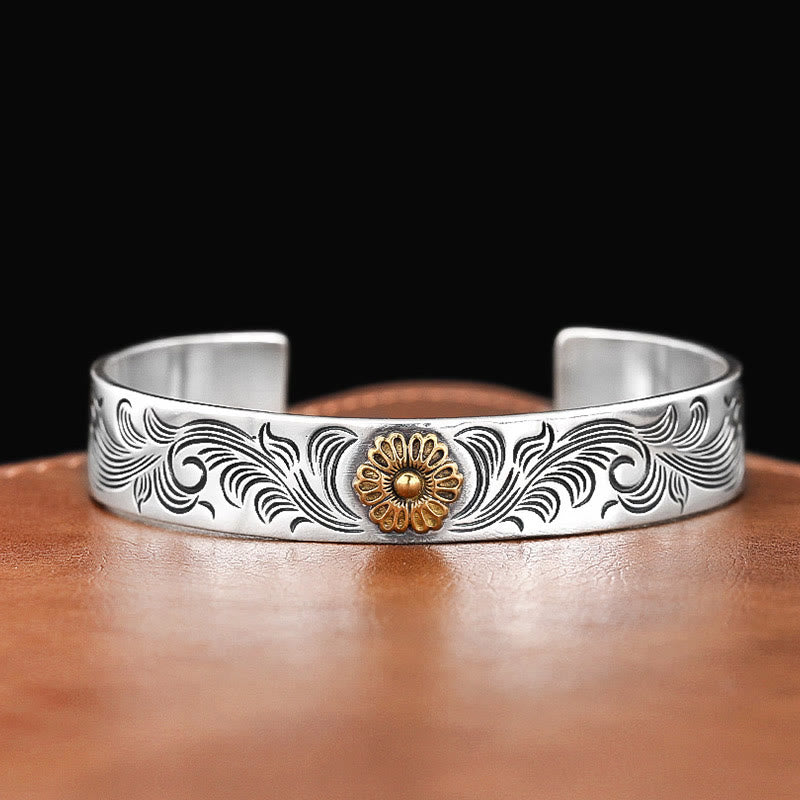 Silbernes Armband mit goldener Blüte auf braunem Leder Hintergrund.
