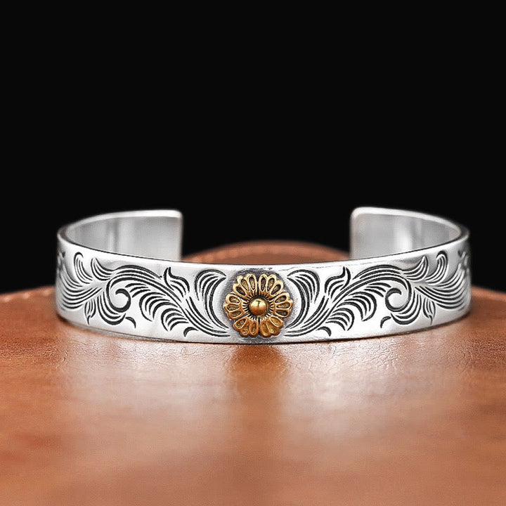 Silbernes Armband mit goldener Blüte auf braunem Leder Hintergrund.