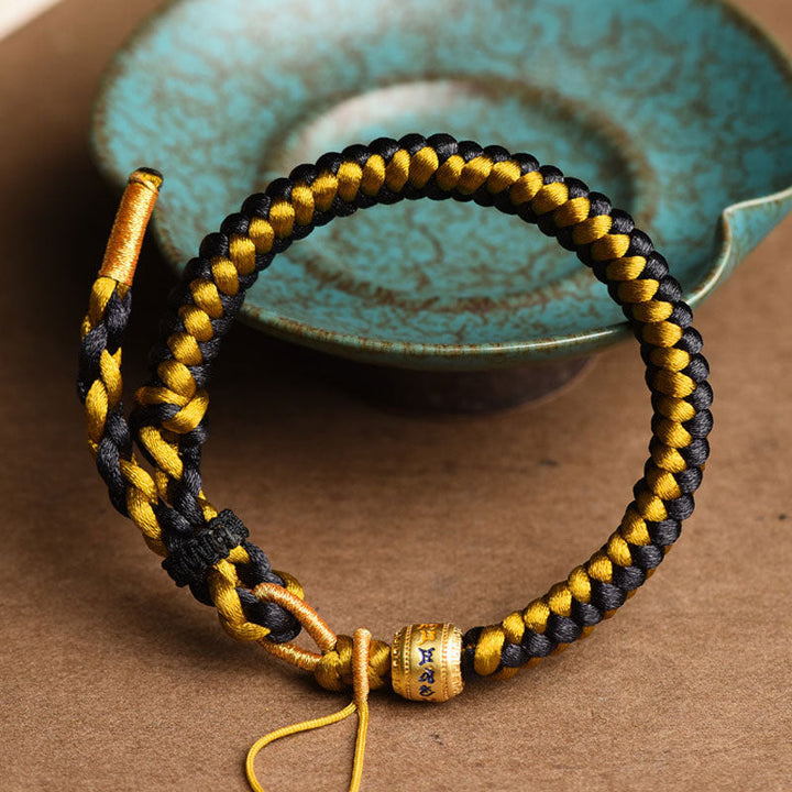 Armband Om Mani Padme Hum Gold schwarze gelbe Schnur geflochten.