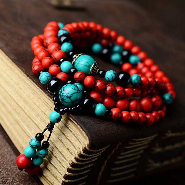 Armband mit roten Perlen und türkisen Steinen auf Buch.